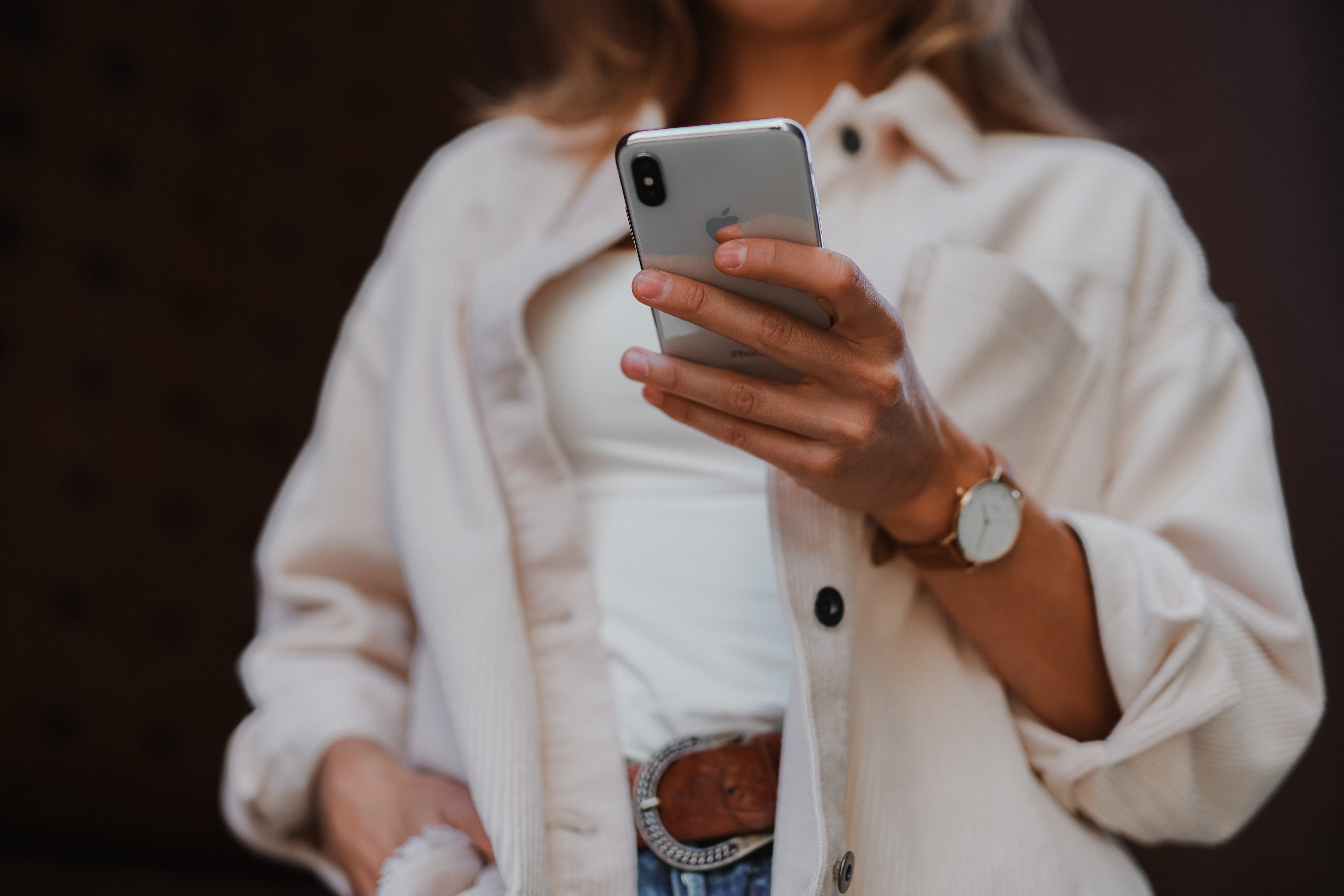 woman in white jacket holding a cell phone